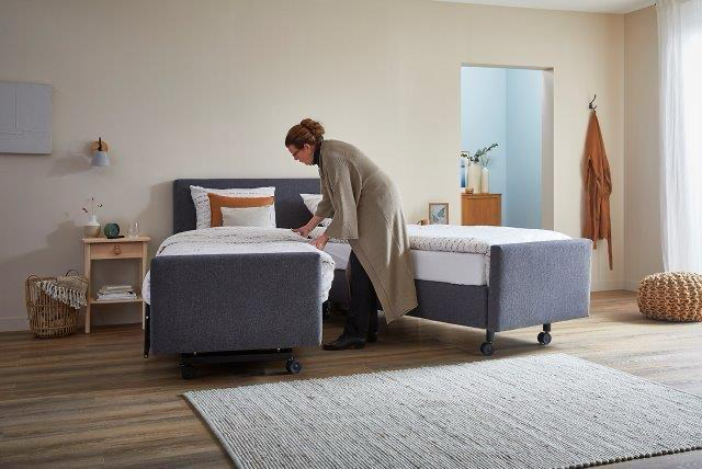 Twee uit elkaar gereden helften van een gestoffeerd deelbaar bed tijdens het opmaken